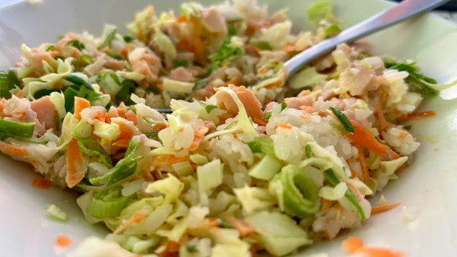 Coleslaw mixed into a salmon rice bowl with spring onions