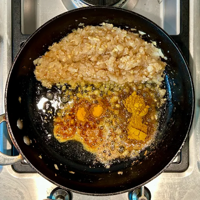 Minimally browned onions, with ginger and garlic, and space to fry curry powder and turmeric in the oil