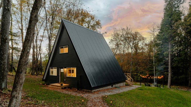 An A-frame tiny house in a woodland clearing