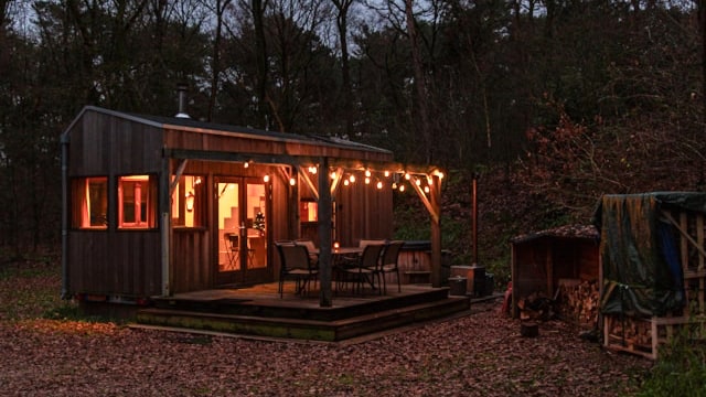 A container-shaped tiny house at dusk with outside lights